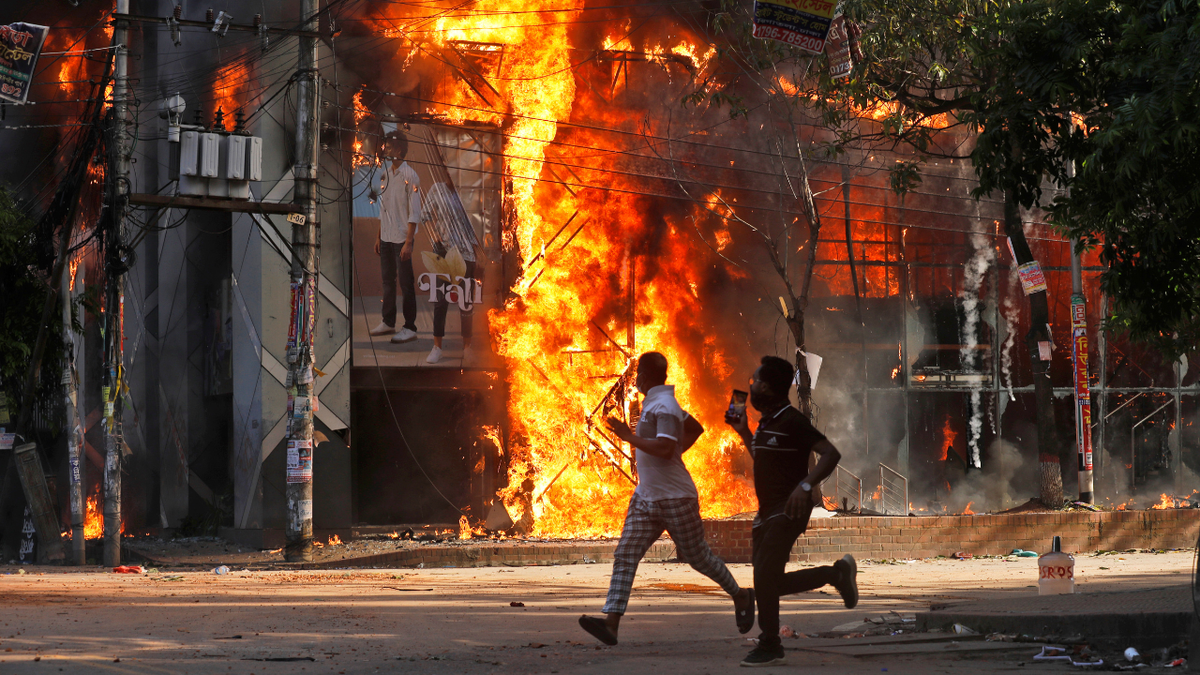 Men run past a shopping mall that was set on fire