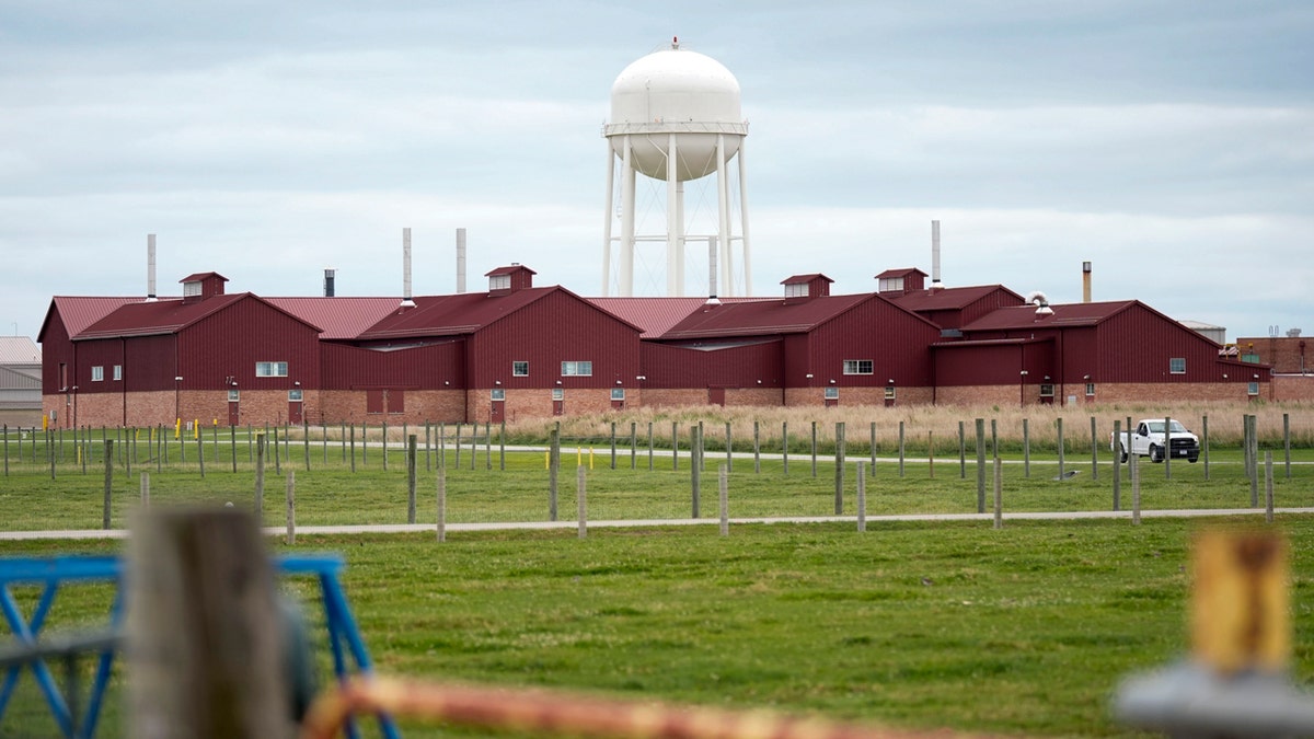 Una torre de agua blanca se alza sobre la instalación roja de contención de animales en el campus de las instalaciones de investigación del Centro Nacional de Enfermedades Animales del Departamento de Agricultura de EEUU.