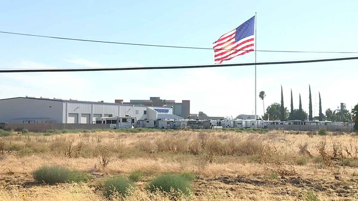 Una bandera gigante de EE.UU. ondea en lo alto de un mástil de 130 pies de altura fuera del Campamento Francés del minorista de vehículos recreativos Camping World, California.