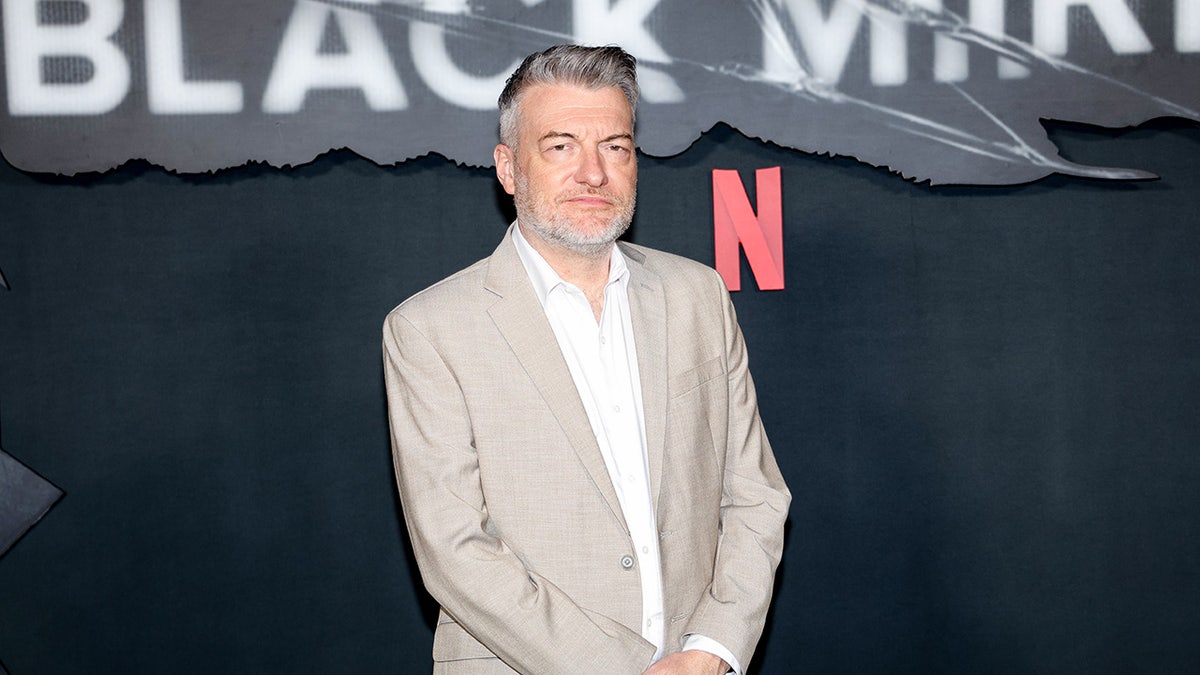 Charlie Brooker in front of the Black Mirror sign