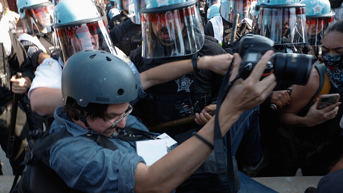 Riot police officers scuffle with a photographer during the rally "March on the DNC" on the sidelines of the Democratic National Convention