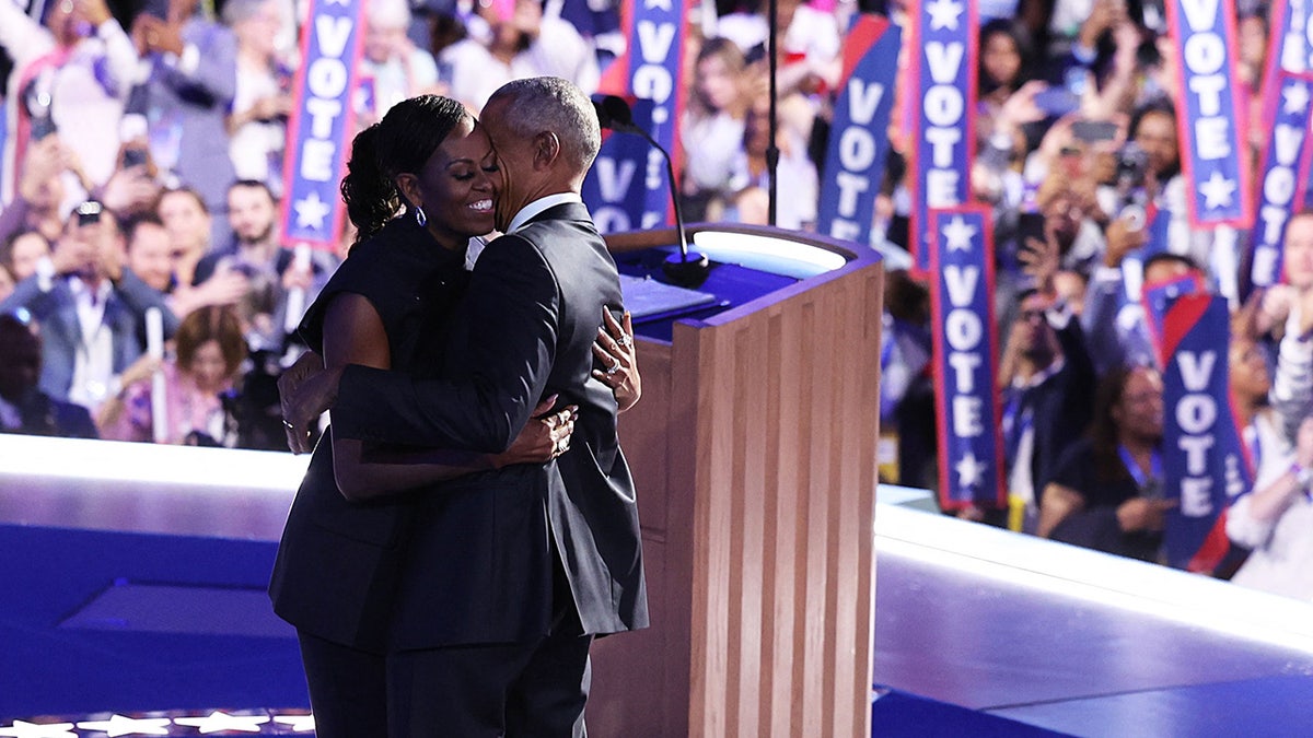 Michelle Obama embraces her husband, former U.S. President Barack Obama, on stage during Day 2 of the Democratic National Convention