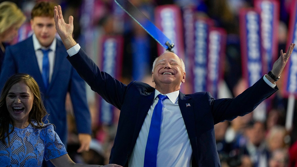 Tim Walz brazos arriba, ojos cerrados feliz en el DNC 