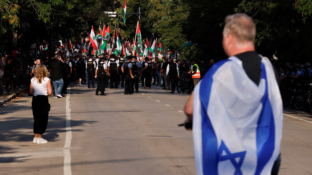 Man with Israel flag looks at anti-Israel protesters outside DNC in Chicago