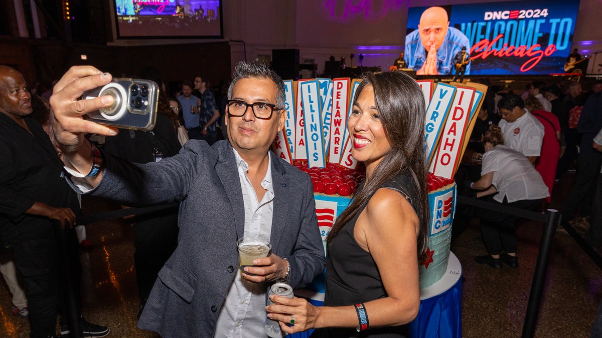 Attendees of the Democratic National Convention media party take a selfie in front of a giant 1,000-pound cheesecake, Aug. 18, 2024, in Chicago.