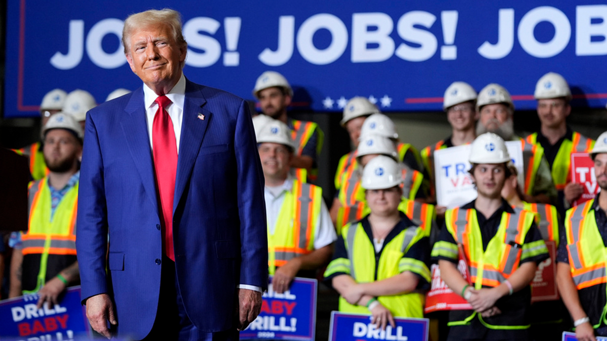 ¡Donald Trump con abrigo azul, corbata roja y un cartel que dice "Jobs!