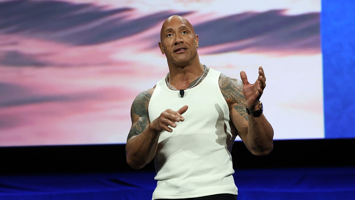 Dwayne Johnson memberi isyarat di atas panggung