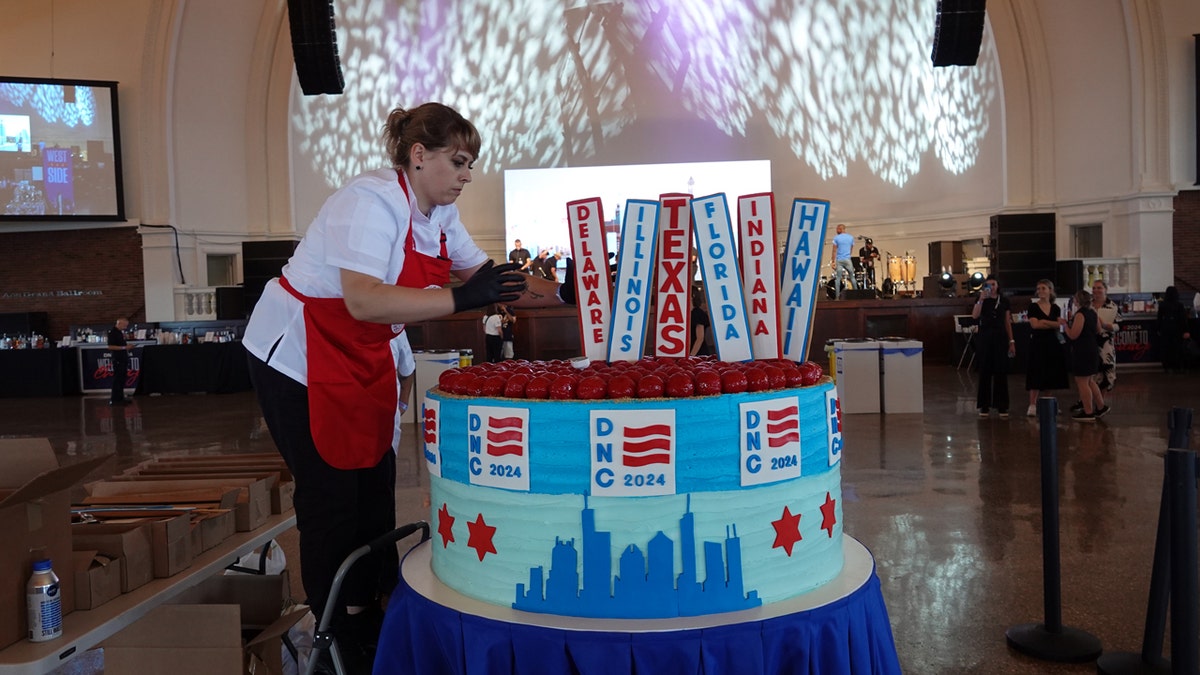 Eli's Cheesecake pastry chef Ivanna Yatskiv places one of 50 state placards on a giant cheesecake ahead of the Democratic National Convention media party, Aug. 17, 2024, in Chicago.