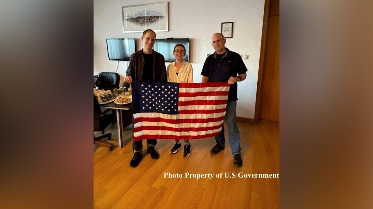 Evan Gershkovich, Alsu Kurmasheva, and Paul Whelan pose with a U.S. flag as they celebrate their freedom