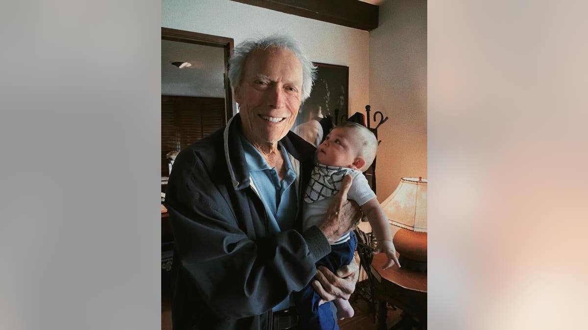 clint eastwood beaming as he holds his grandson titan