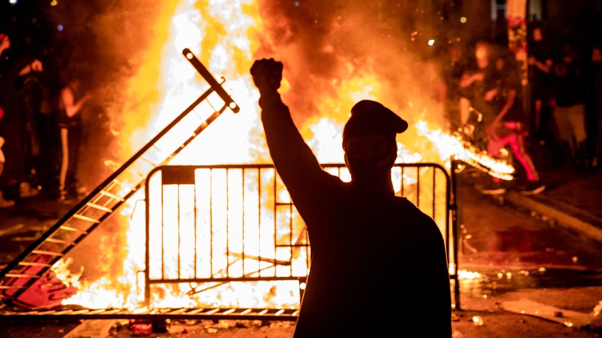 Un manifestante levanta el puño cerca de un incendio