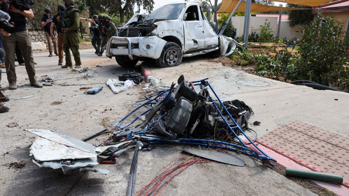 Soldados y periodistas israelíes se reúnen alrededor de un parapente motorizado dañado utilizado por terroristas de Hamas en Kfar Aza, al sur de Israel, en la frontera con la Franja de Gaza, el 10 de octubre de 2023.