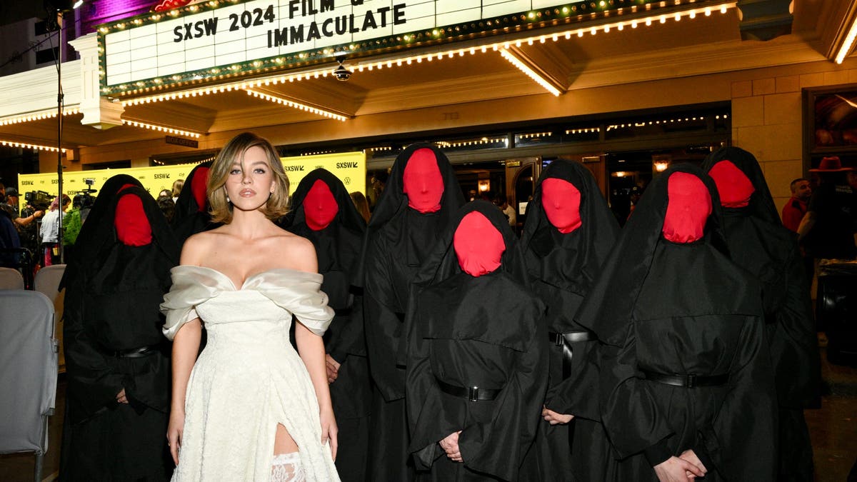 sydney sweeney posando con personas vestidas de monjas con la cara cubierta con máscaras rojas en el estreno de inmaculada en el SXSW