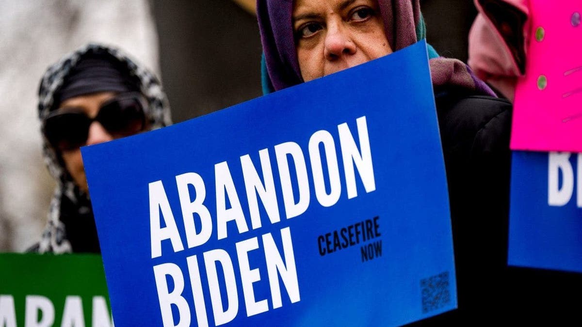 Manifestantes del grupo "Abandonen a Biden" sostienen pancartas durante una rueda de prensa previa a la visita del presidente Joe Biden en Saginaw, Michigan, el jueves 14 de marzo de 2024.