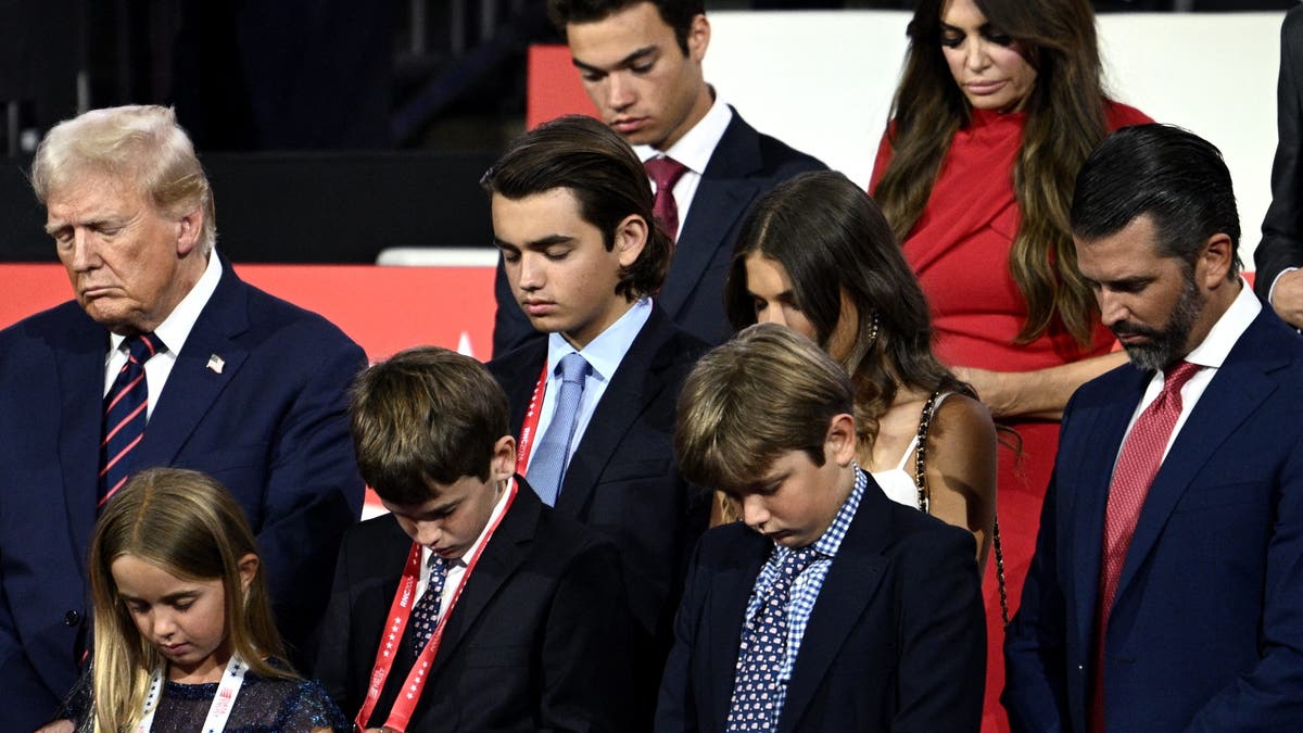 US former President and 2024 Republican presidential candidate Donald Trump bows in prayer alongside his grandchildren during the third day of the 2024 Republican National Convention at the Fiserv Forum in Milwaukee, Wisconsin, on July 17, 2024. Days after he survived an assassination attempt Donald Trump won formal nomination as the Republican presidential candidate and picked Ohio US Senator J.D. Vance for running mate. (Photo by Brendan SMIALOWSKI / AFP) (Photo by BRENDAN SMIALOWSKI/AFP via Getty Images)