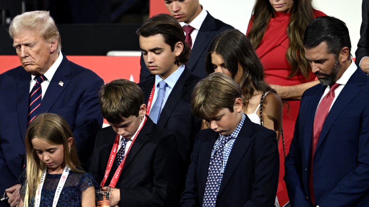US former President and 2024 Republican presidential candidate Donald Trump bows in prayer alongside his grandchildren during the third day of the 2024 Republican National Convention at the Fiserv Forum in Milwaukee, Wisconsin, on July 17, 2024. Days after he survived an assassination attempt Donald Trump won formal nomination as the Republican presidential candidate and picked Ohio US Senator J.D. Vance for running mate. (Photo by Brendan SMIALOWSKI / AFP) (Photo by BRENDAN SMIALOWSKI/AFP via Getty Images)