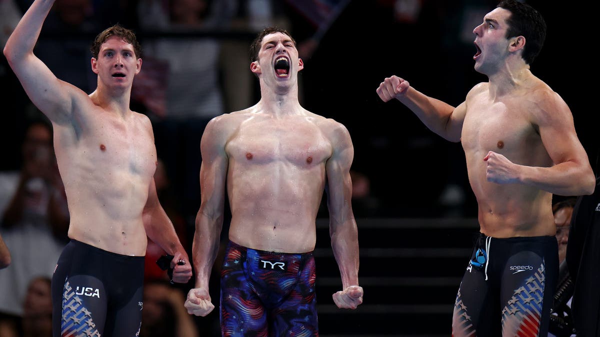 Chris Guiliano (izquierda), Hunter Armstrong (centro) y Jack Alexy (derecha) del Equipo de Estados Unidos celebran tras ganar el oro en la final masculina de relevos 4x100m estilo libre.