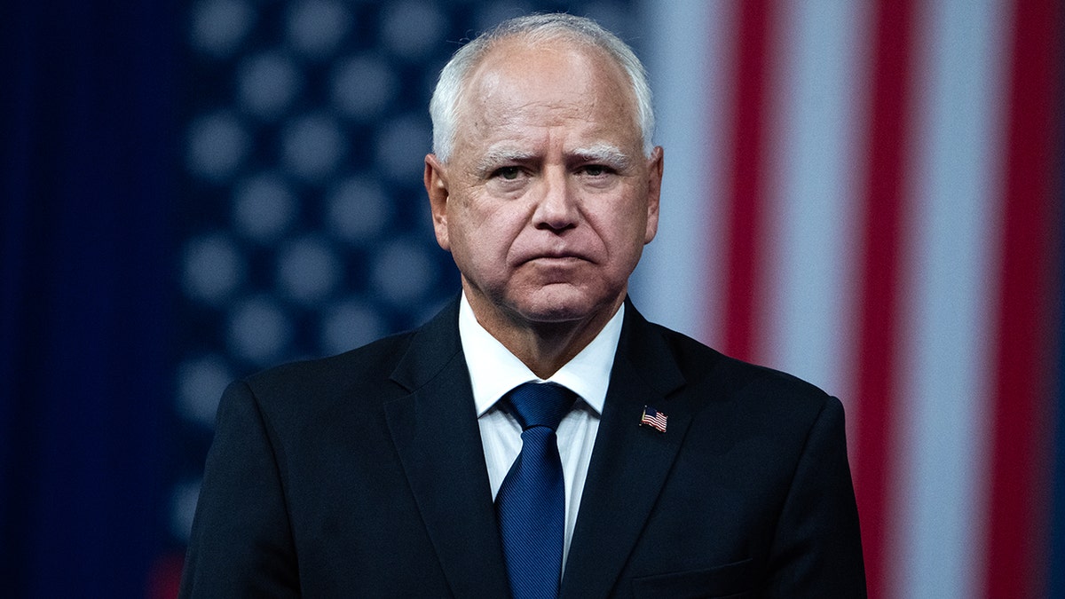 Minnesota Gov. Tim Walz stands in front of an American flag