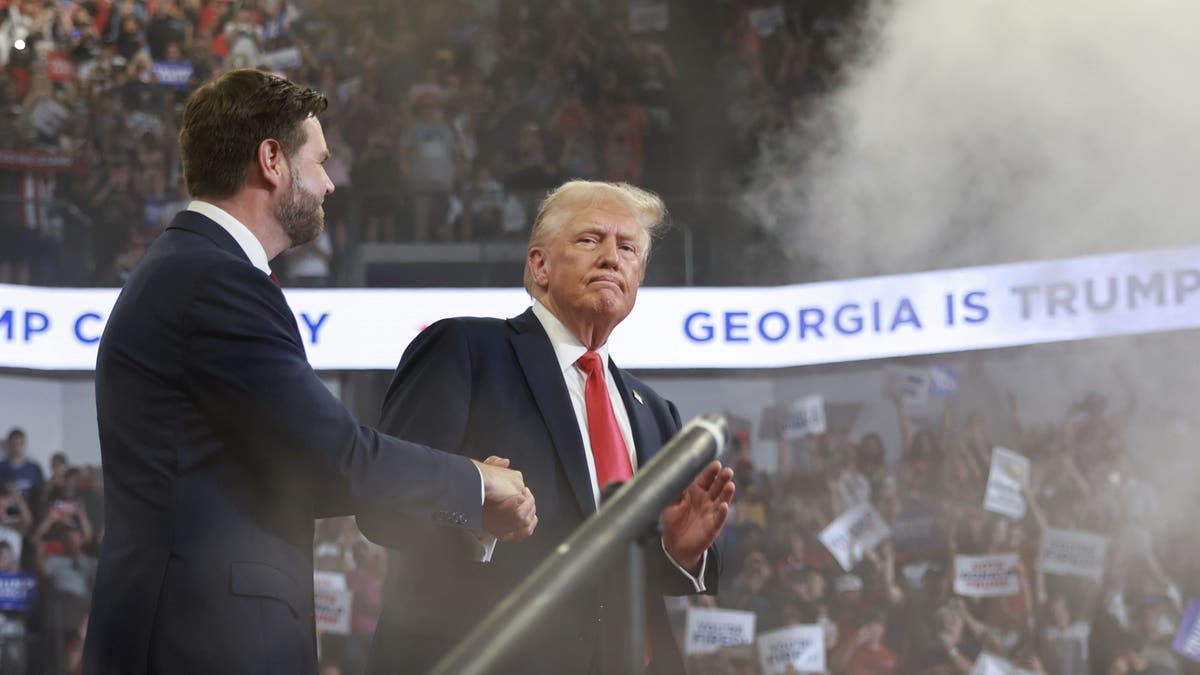 El candidato presidencial republicano Donald Trump sube al escenario con su compañero de fórmula para la vicepresidencia, el senador JD Vance, durante un mitin de campaña en el Centro de Convocatoria de la Universidad Estatal de Georgia, en Atlanta, el 3 de agosto de 2024.