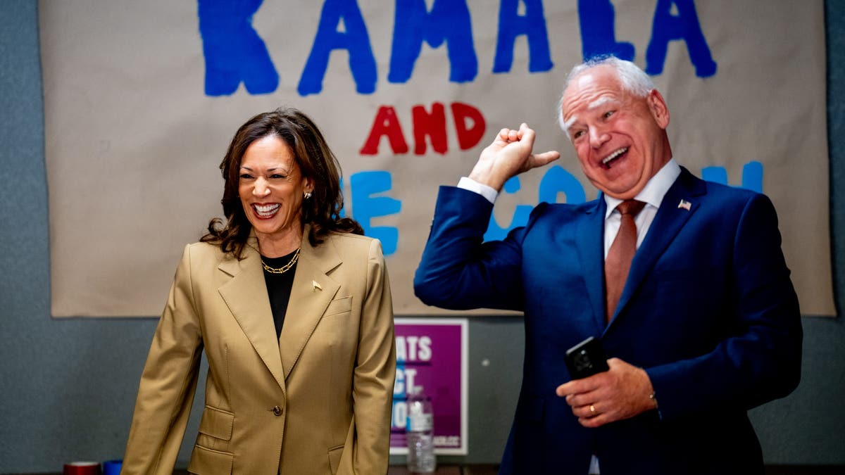 Vice President Kamala Harris and Minnesota Gov. Tim Walz laugh after taking a selfie in front of a sign that reads "Kamala and The Coach" during a stop at a campaign office on Aug. 9, 2024 in Glendale, Arizona. (Andrew Harnik/Getty Images)