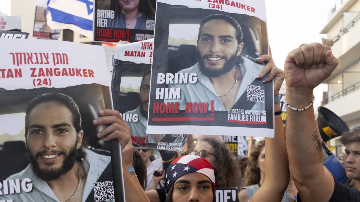 Familiares de rehenes que fueron secuestrados por Hamas en el ataque mortal del 7 de octubre y partidarios sostienen carteles y banderas estadounidenses durante una manifestación frente a un evento de prensa del Secretario de Estado de Estados Unidos, Antony Blinken, el 19 de agosto de 2024, en Tel Aviv, Israel. 