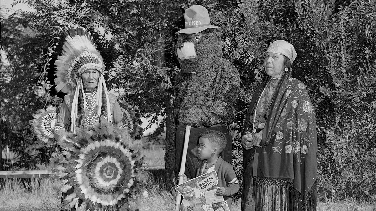 Smokey the Bear, Flathead (Salish) chief Paul Charlo, his wife, and young Allen Thompson pose.