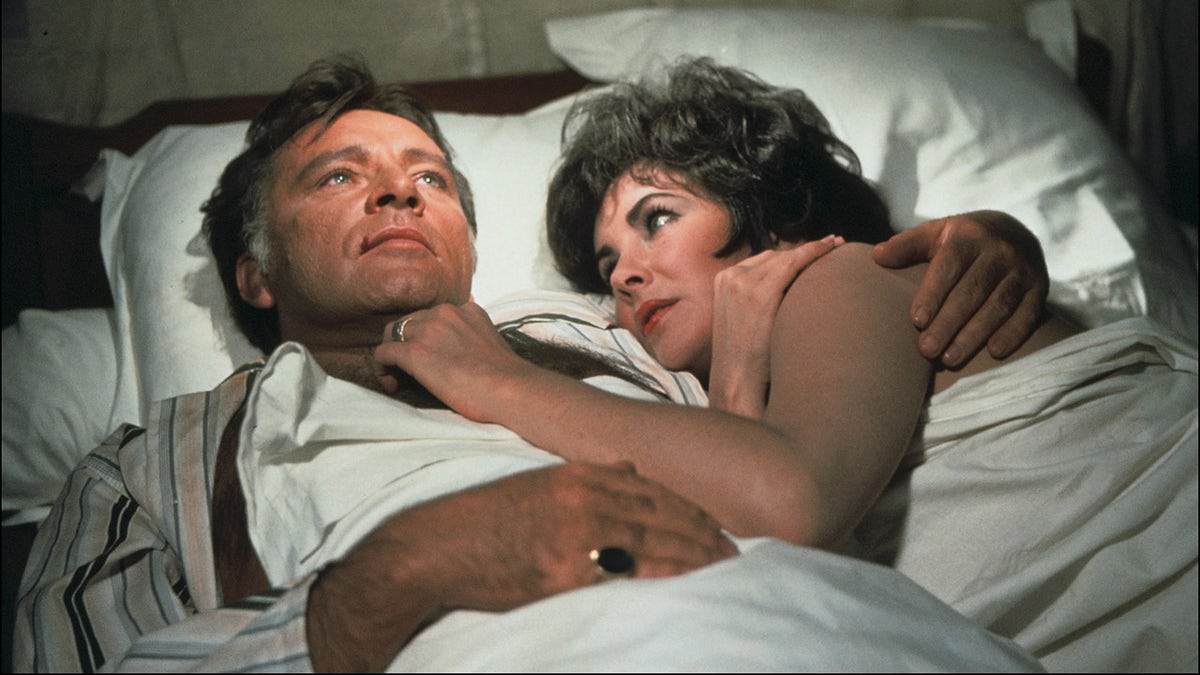 Elizabeth Taylor and Richard Burton laying in bed.