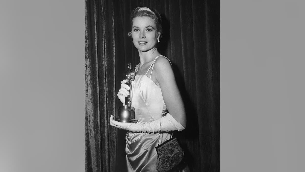 Grace Kelly wearing a white spaghetti strap dress holding her Oscar.