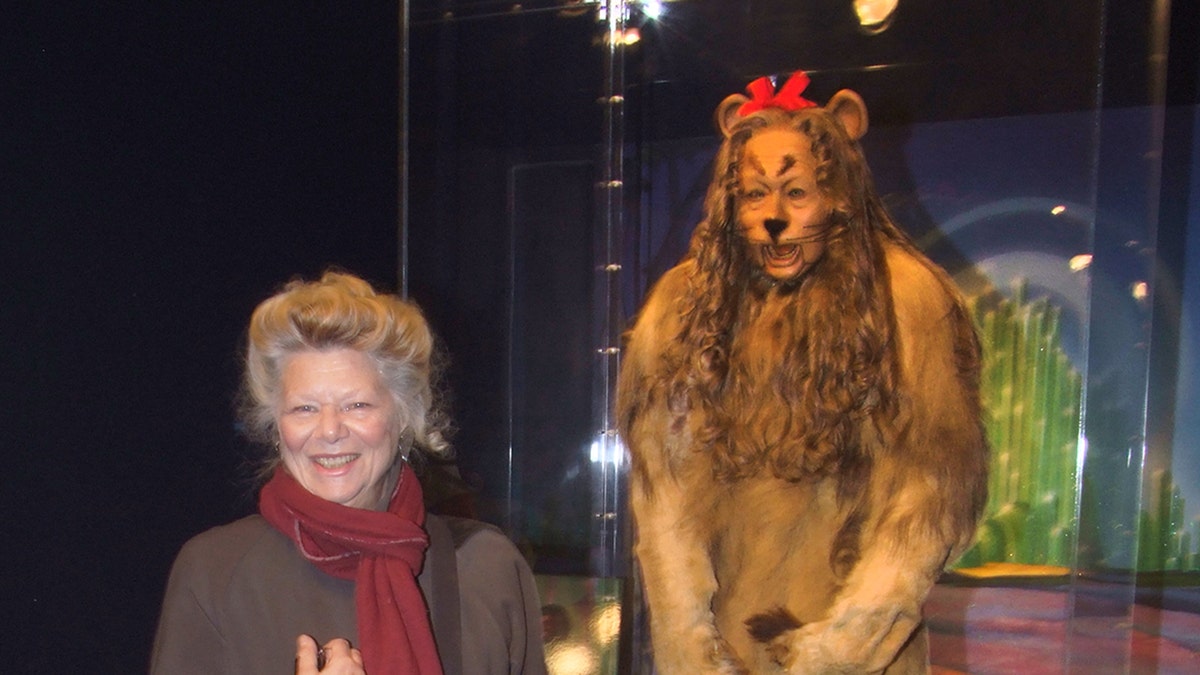 Jane Lahr posing next to her fathers Cowardly Lion costume.