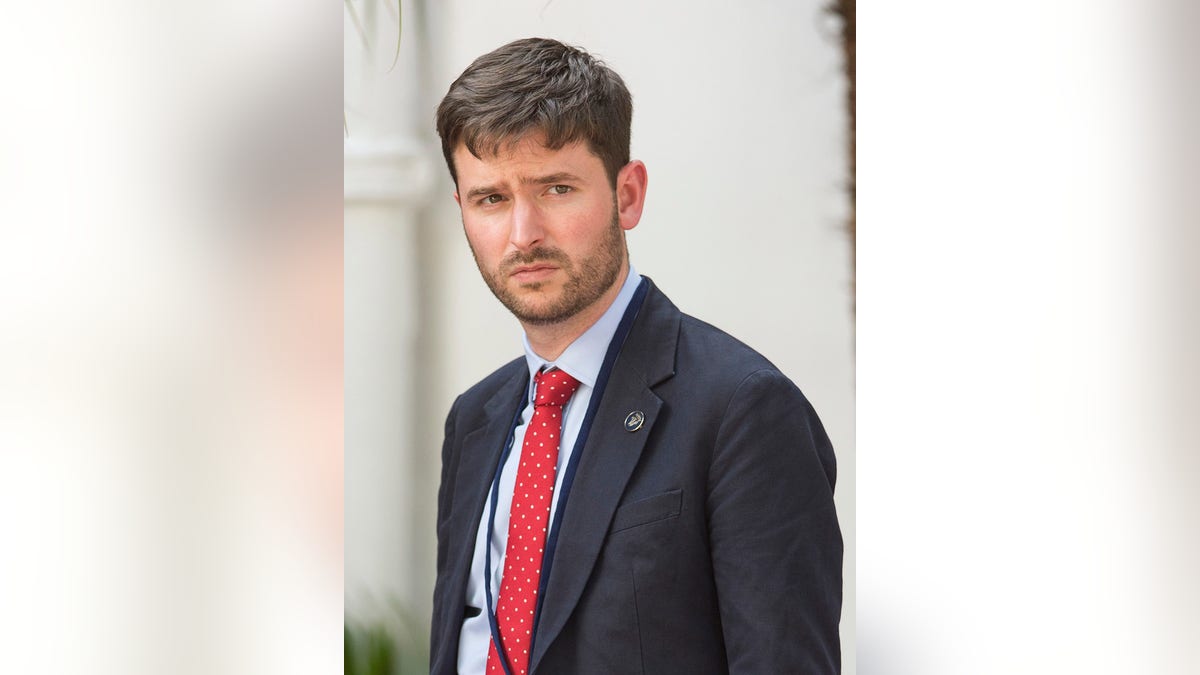 Jason Knauf con traje oscuro y corbata roja.