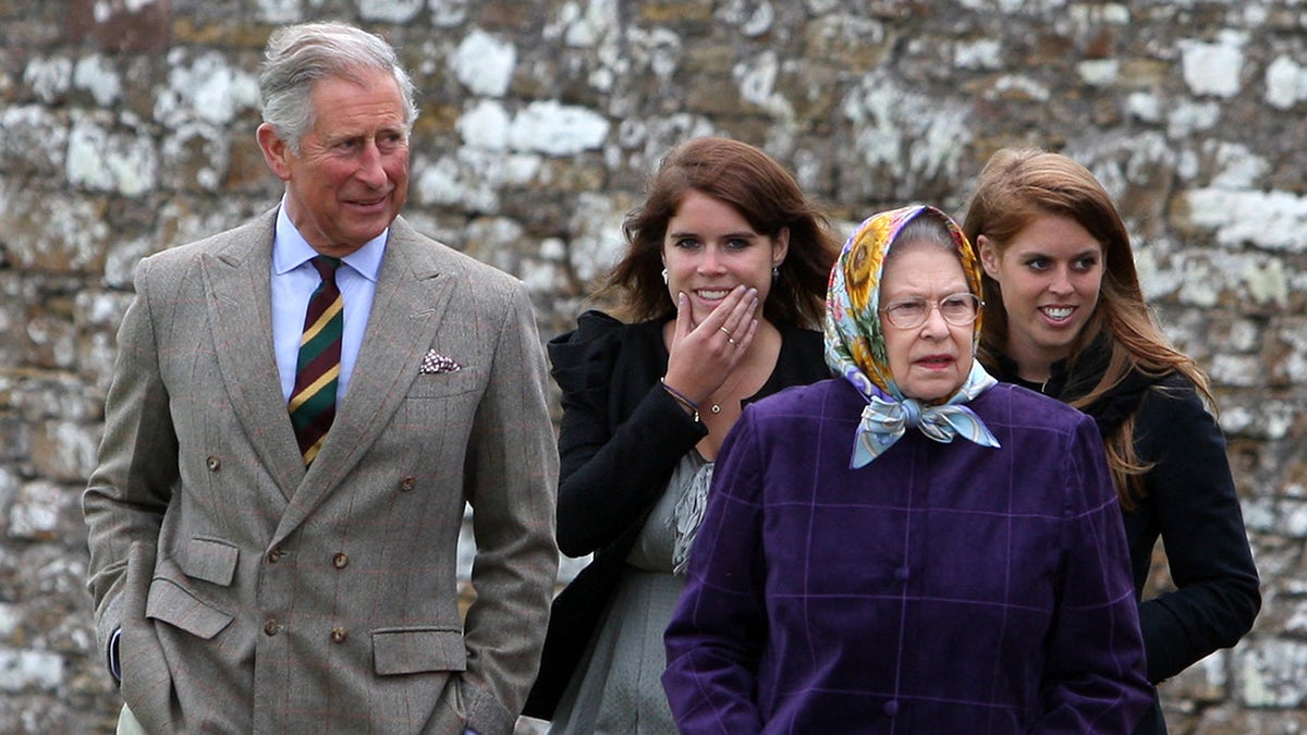 King Charles in a grey suit walking next to Queen Elizabeth II and his nieces Princess Eugenie and Princess Beatrice