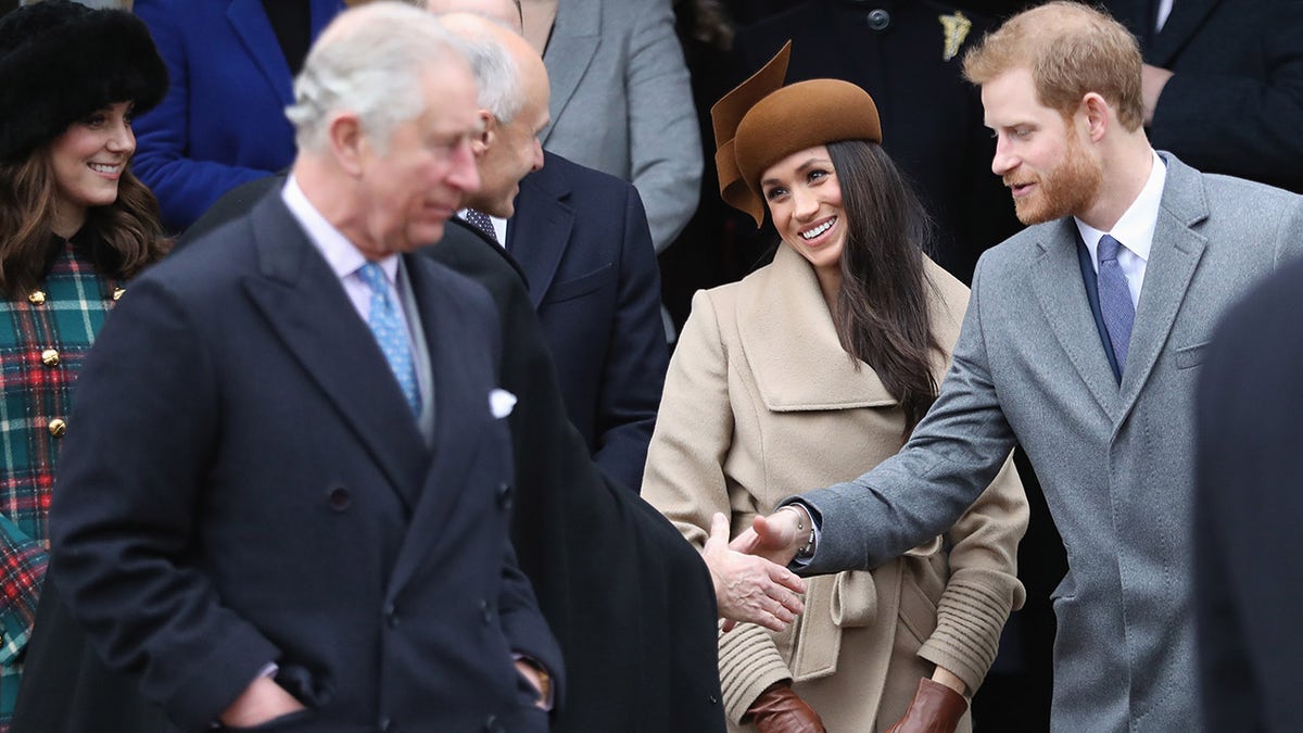 King Charles looking away as Prince Harry and Meghan Markle greet an older gentleman.