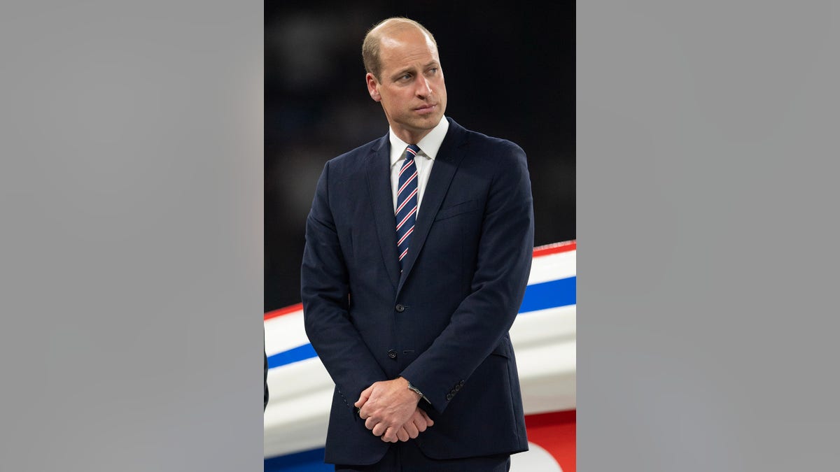 Prince William wearing a navy suit with a striped tie.