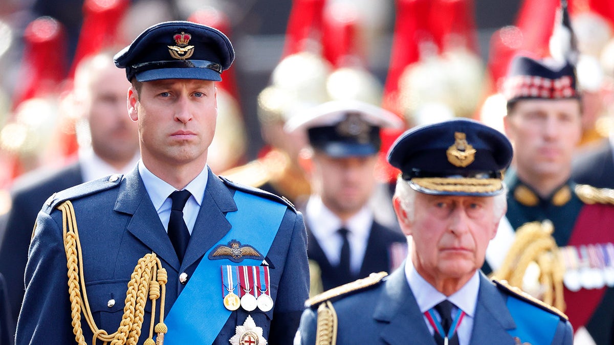 Prince William and King Charles in matching blue military uniforms marching.