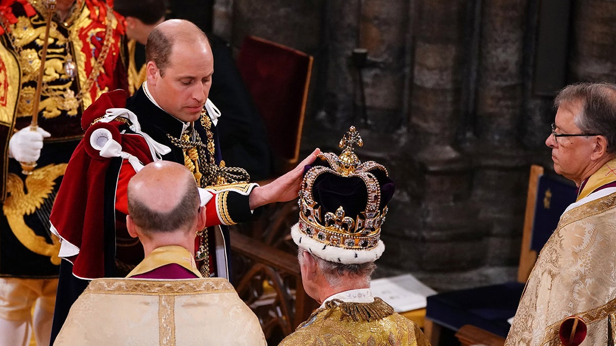 Prince William touching King Charles' crown during his father's coronation ceremony