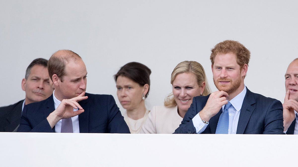 Zara Tindall wearing beige sitting down in between Prince William and Prince Harry.