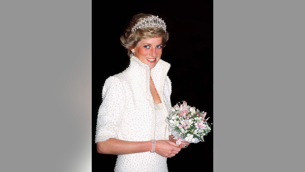 Princess Diana wearing a white dress and a tiara holding a bouquet of flowers.