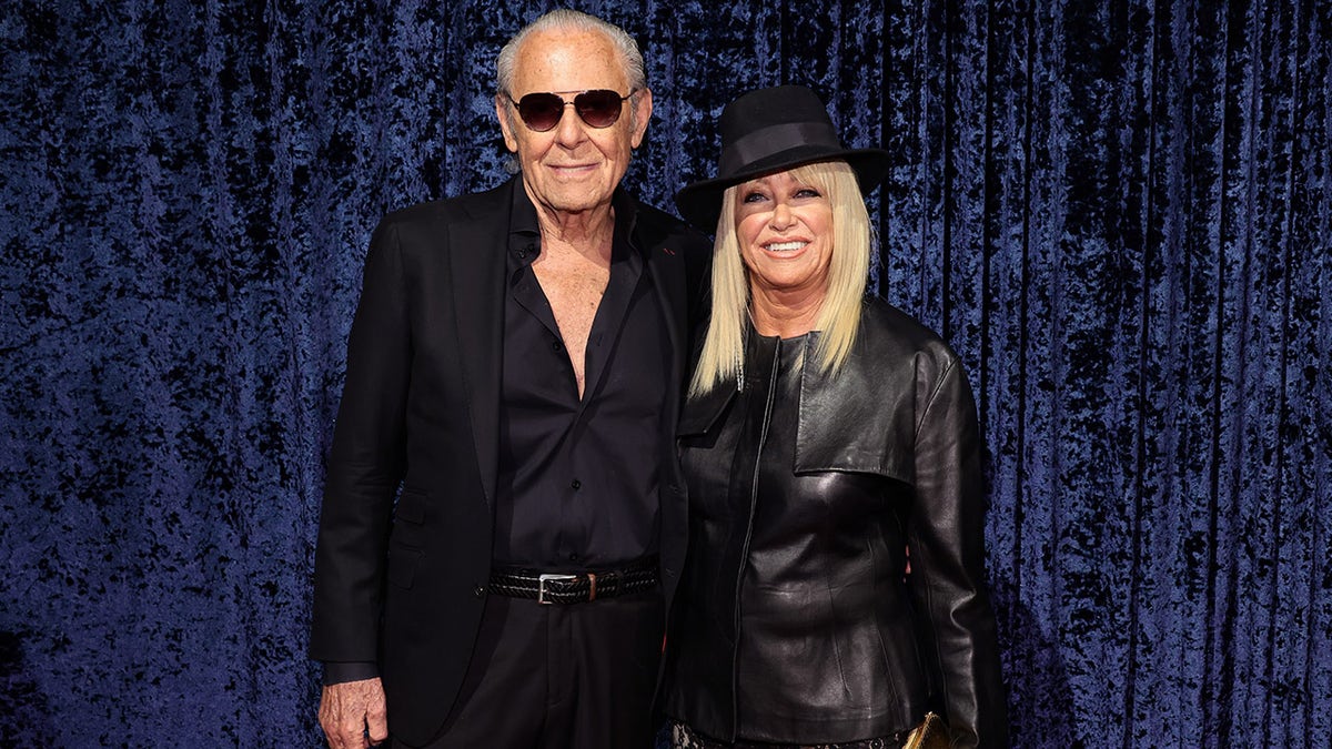Alan Hamel and Suzanne Somers wearing matching black outfits.