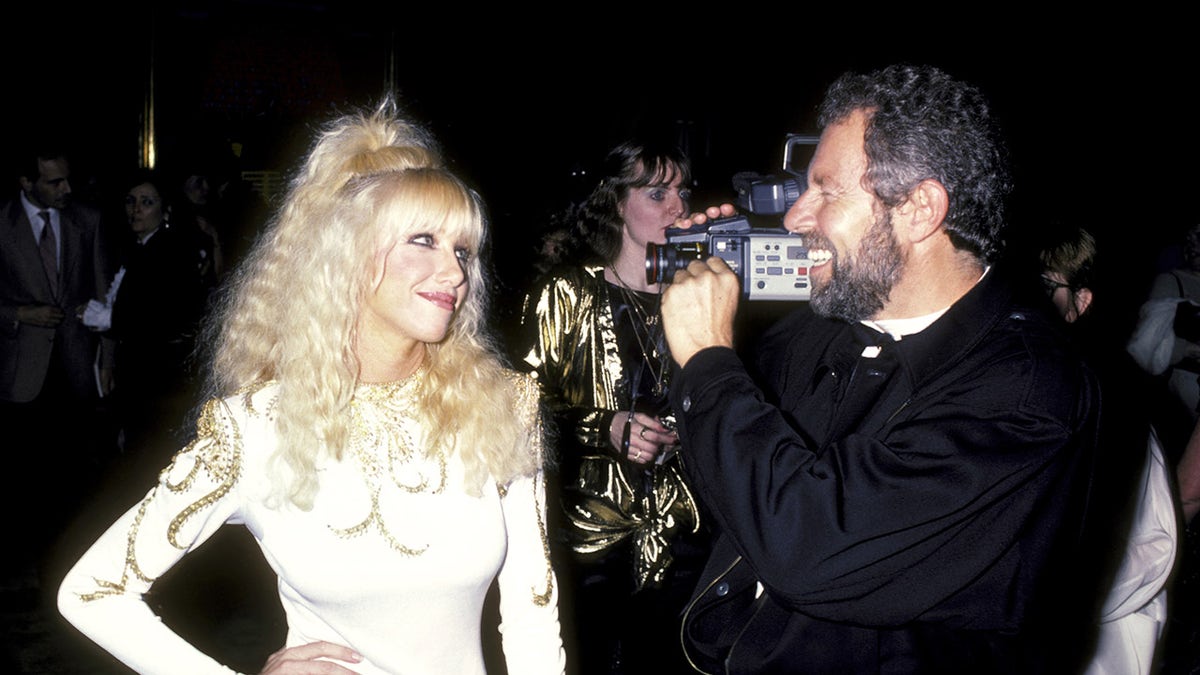 Alan Hamel recording Suzanne Somers from a camera.