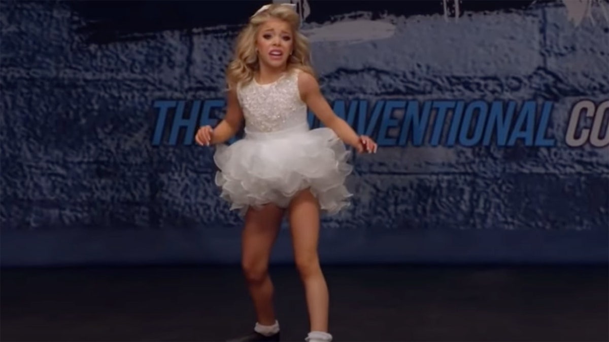 Ashlan dances on stage in a white tutu,