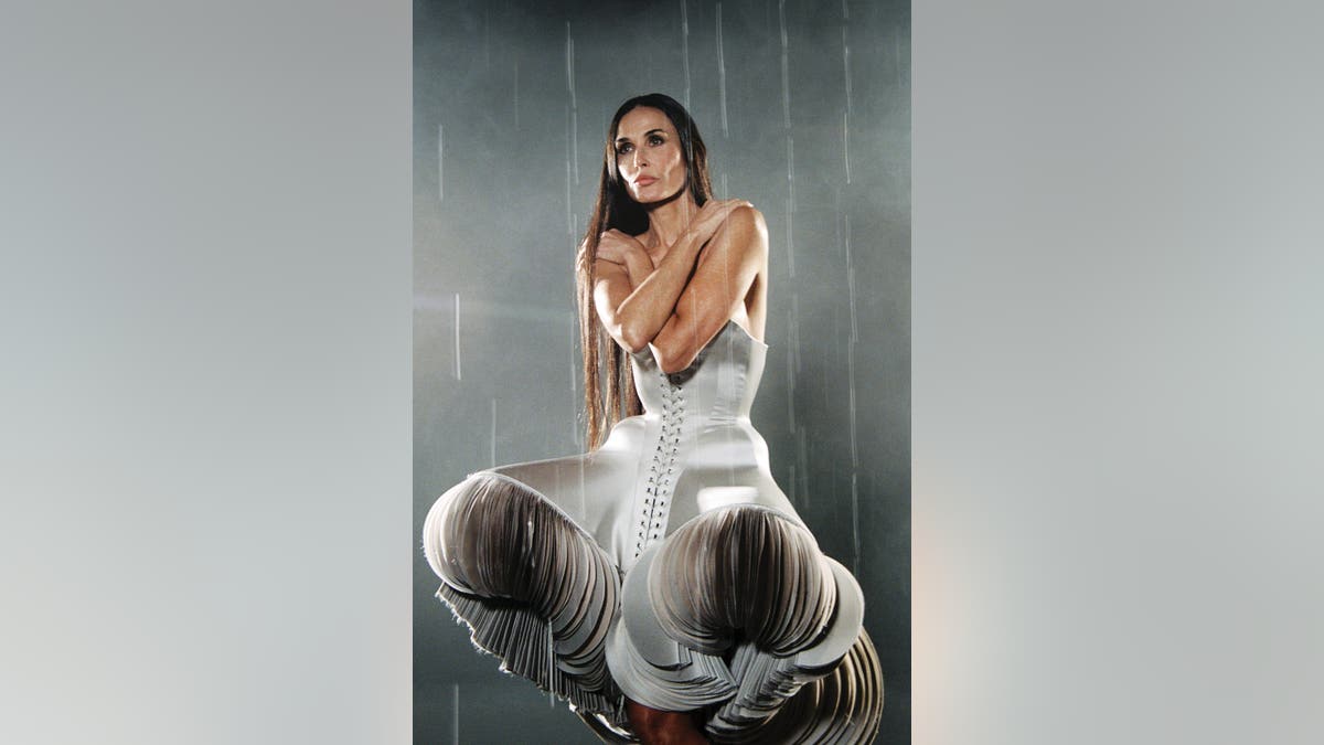 Demi Moore crouching in a silver dress