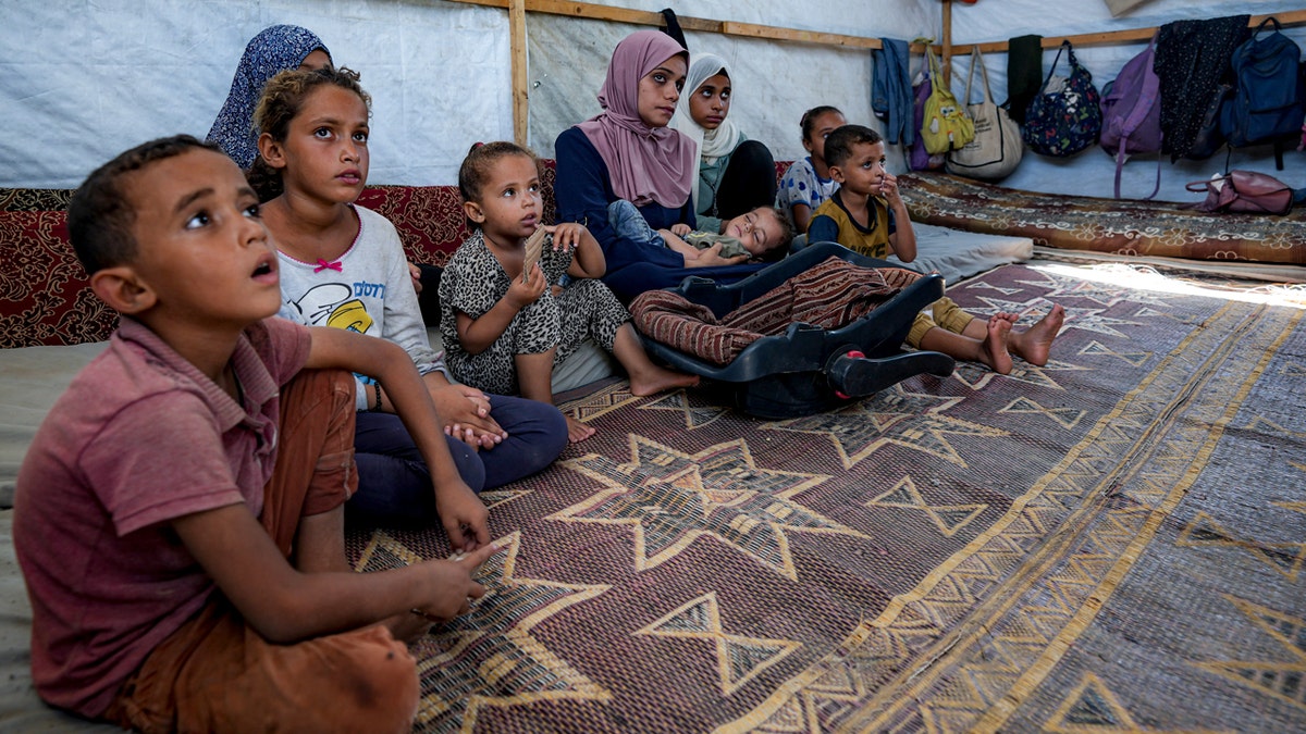 Displaced Gazans gather in a tent camp in Deir al-Balah.