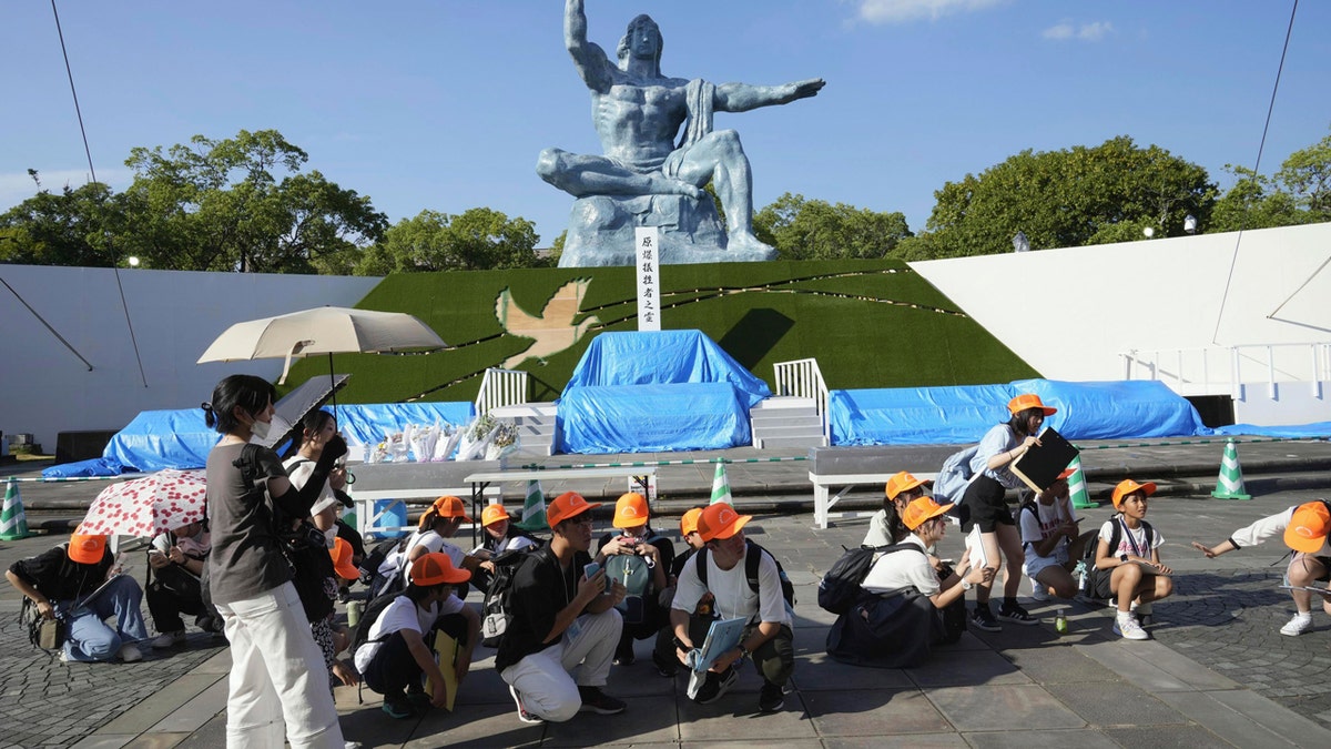 Los visitantes del Parque de la Paz de Nagasaki, con sombreros amarillos, se agachan después de que se emite una alerta de terremoto.