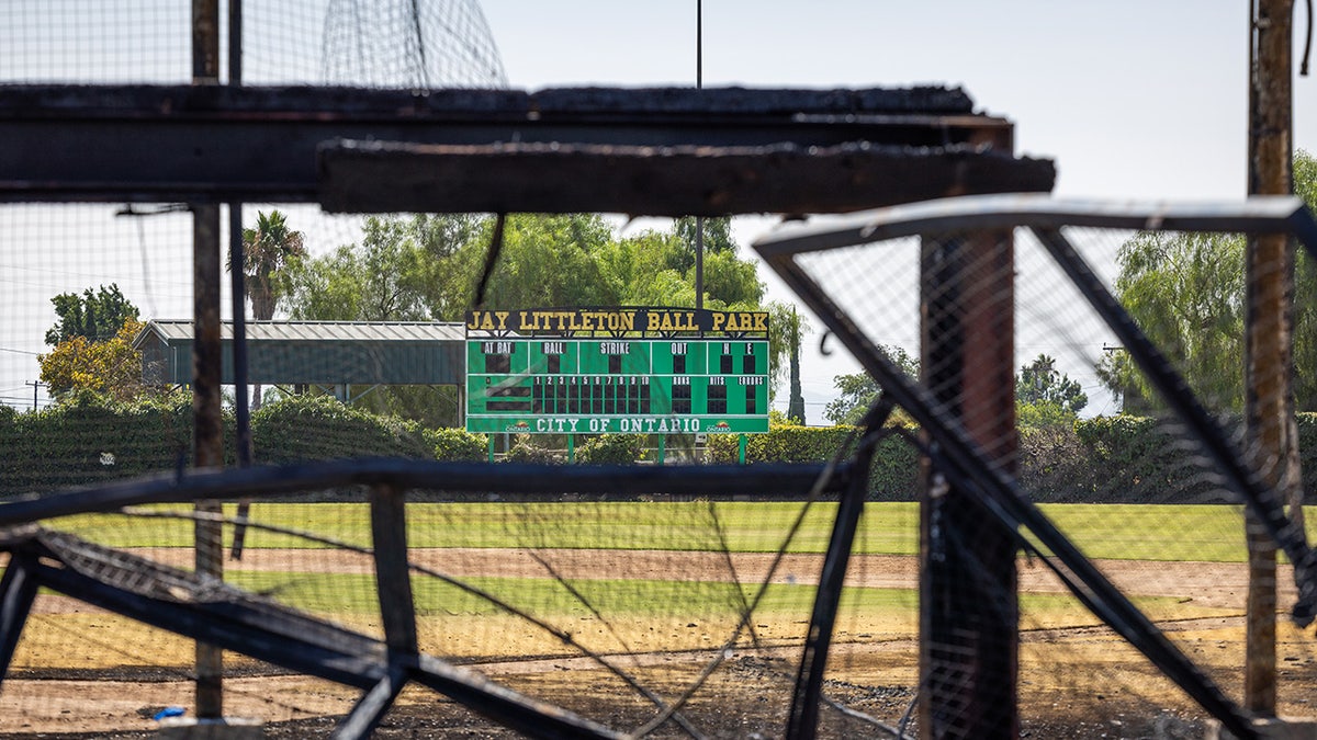 The charred remains of the historic wooden bleachers and dugouts frame the view of the scoreboard after a fire destroyed the historic baseball field at Jay Littleton Ball Park in Ontario, California, late Thursday morning.