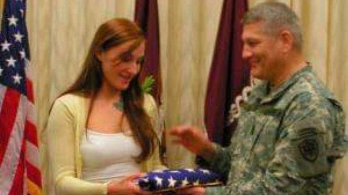 Jennifer Horn accepting an American flag from a soldier.