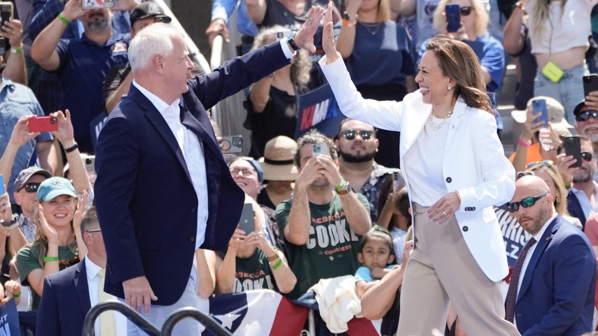 Tim Walz y Kamala Harris en un mitin chocando las manos