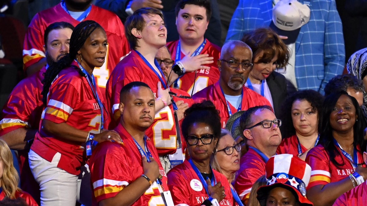 Delegates from Kansas stand for the US national anthem.