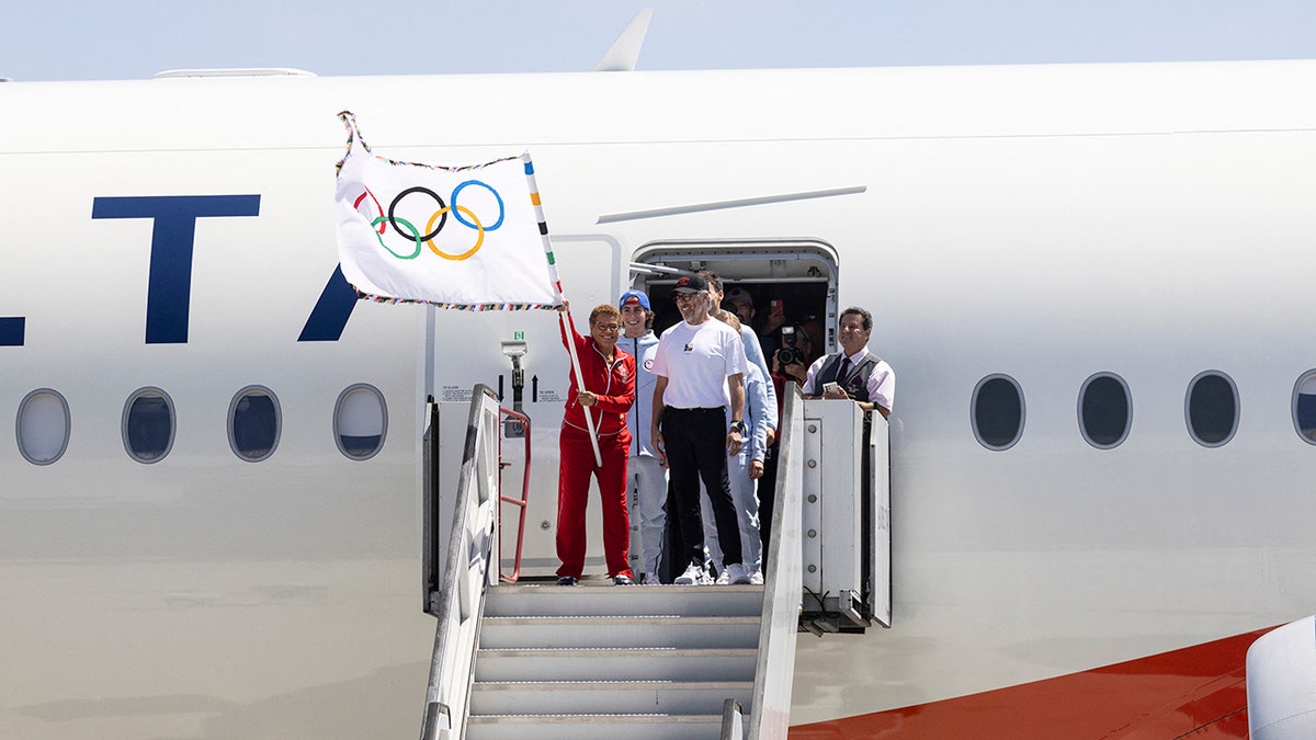 Karen Bass Waves Bendera Olimpiade di Pesawat