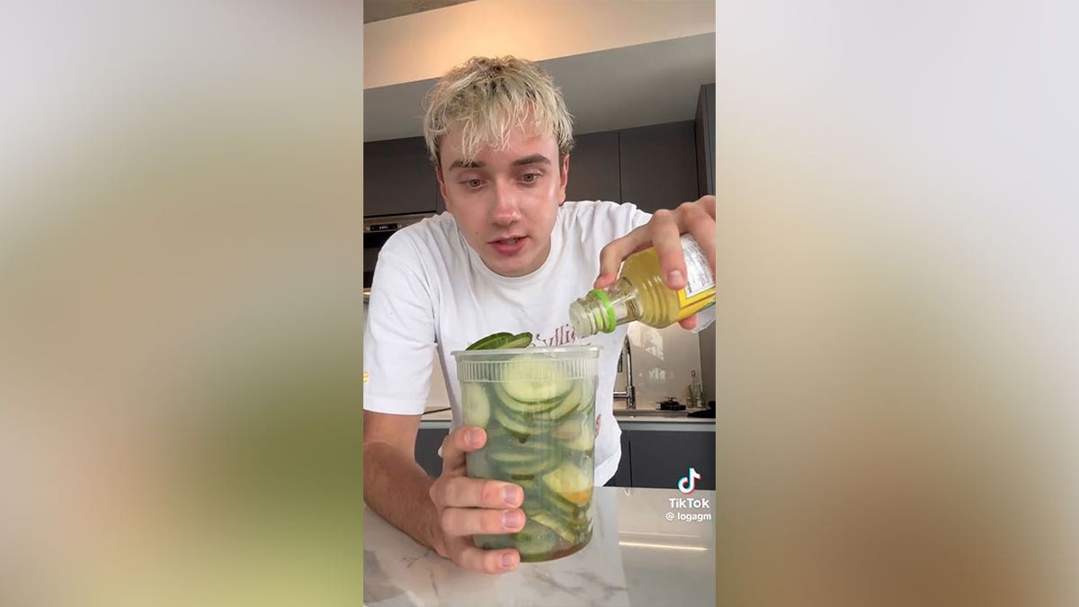 Homem despejando vinagre de arroz em um recipiente com pepinos.