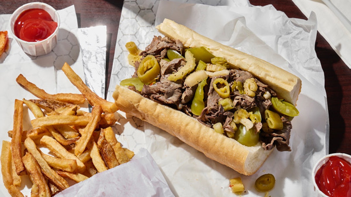 An Italian beef sandwich served with French fries on a plate.
